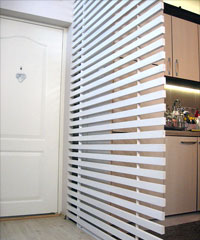 drvena resetka u belij boji kao pregrada iymedju kuhinje i ulaza u stan